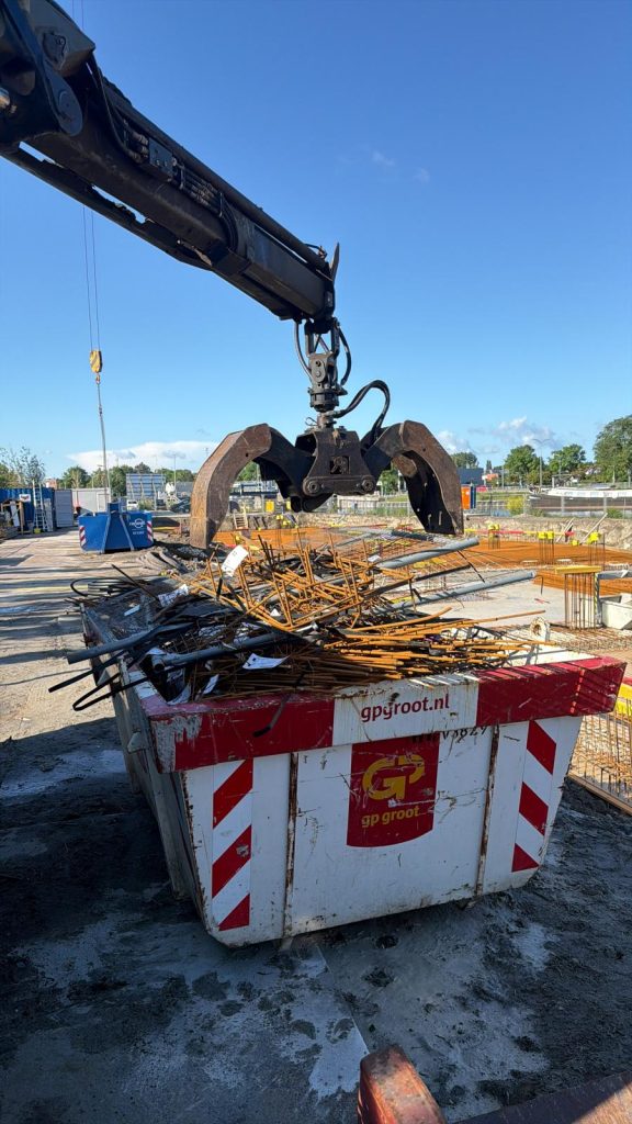 Grijper van Wout Oudijzer laadt betonijzer uit een container op de bouwplaats